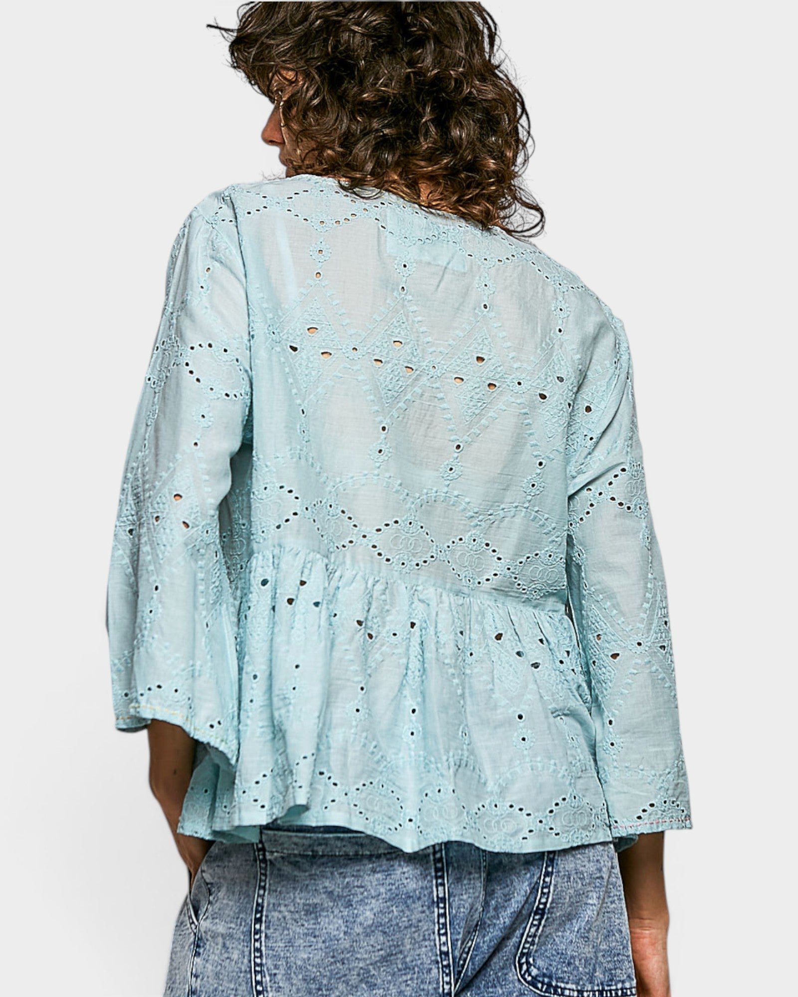 Light blue embroidered blouse worn by a person on a white background