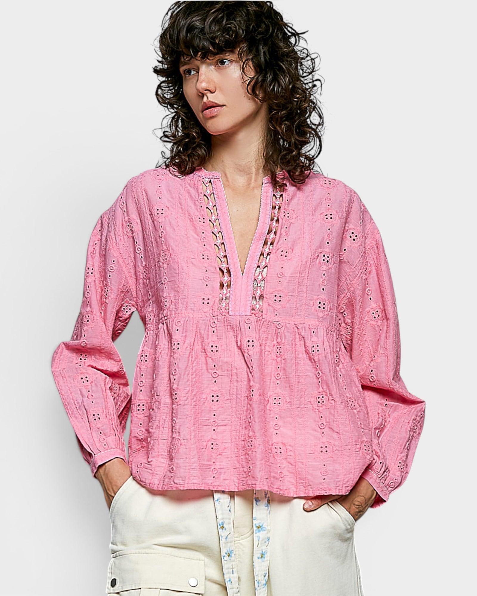 Woman wearing a pink embroidered blouse with a plain background