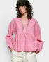 Woman wearing a pink embroidered blouse with a plain background