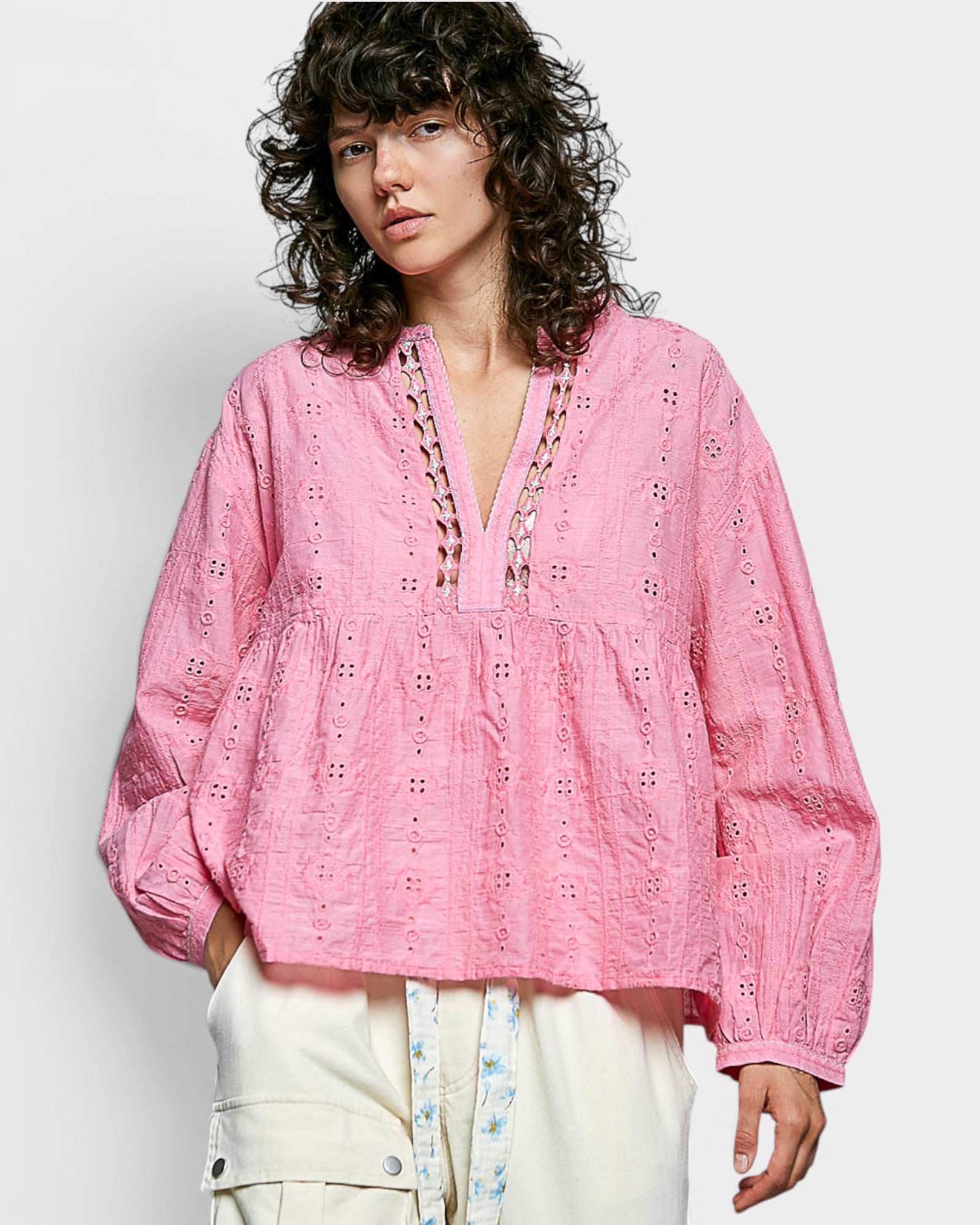 Woman wearing a pink embroidered blouse against a white background