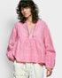 Woman wearing a pink embroidered blouse against a white background