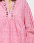 Close-up of a pink embroidered dress with intricate patterns.