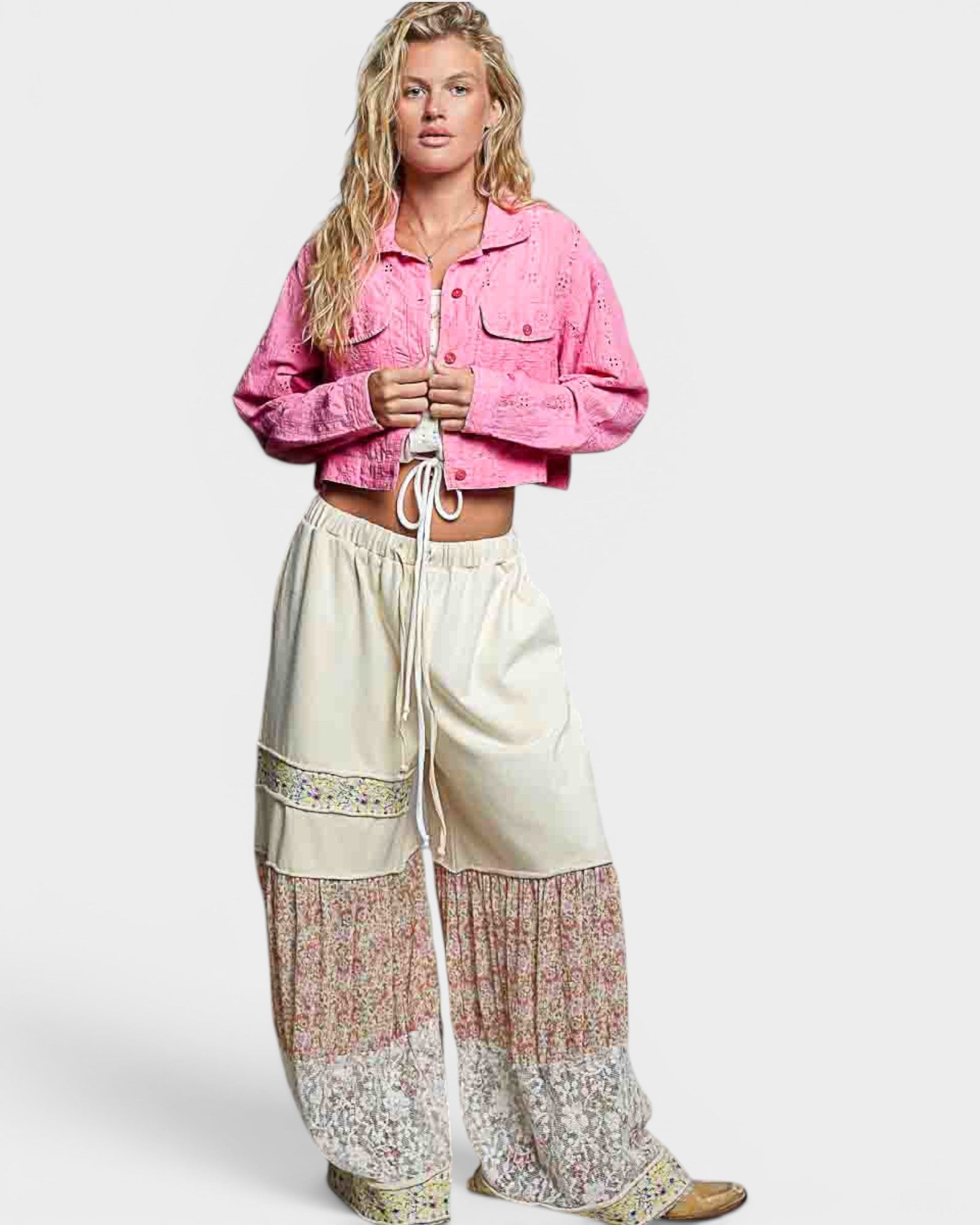 Woman wearing a pink jacket and patterned pants on a white background
