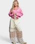 Woman wearing a pink jacket and patterned pants on a white background