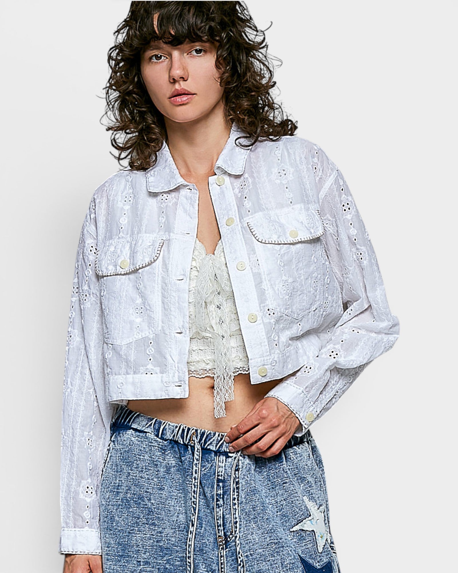 Person wearing an off white embroidered jacket and denim pants on a white background
