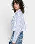 Person wearing an off white embroidered jacket and denim pants on a white background