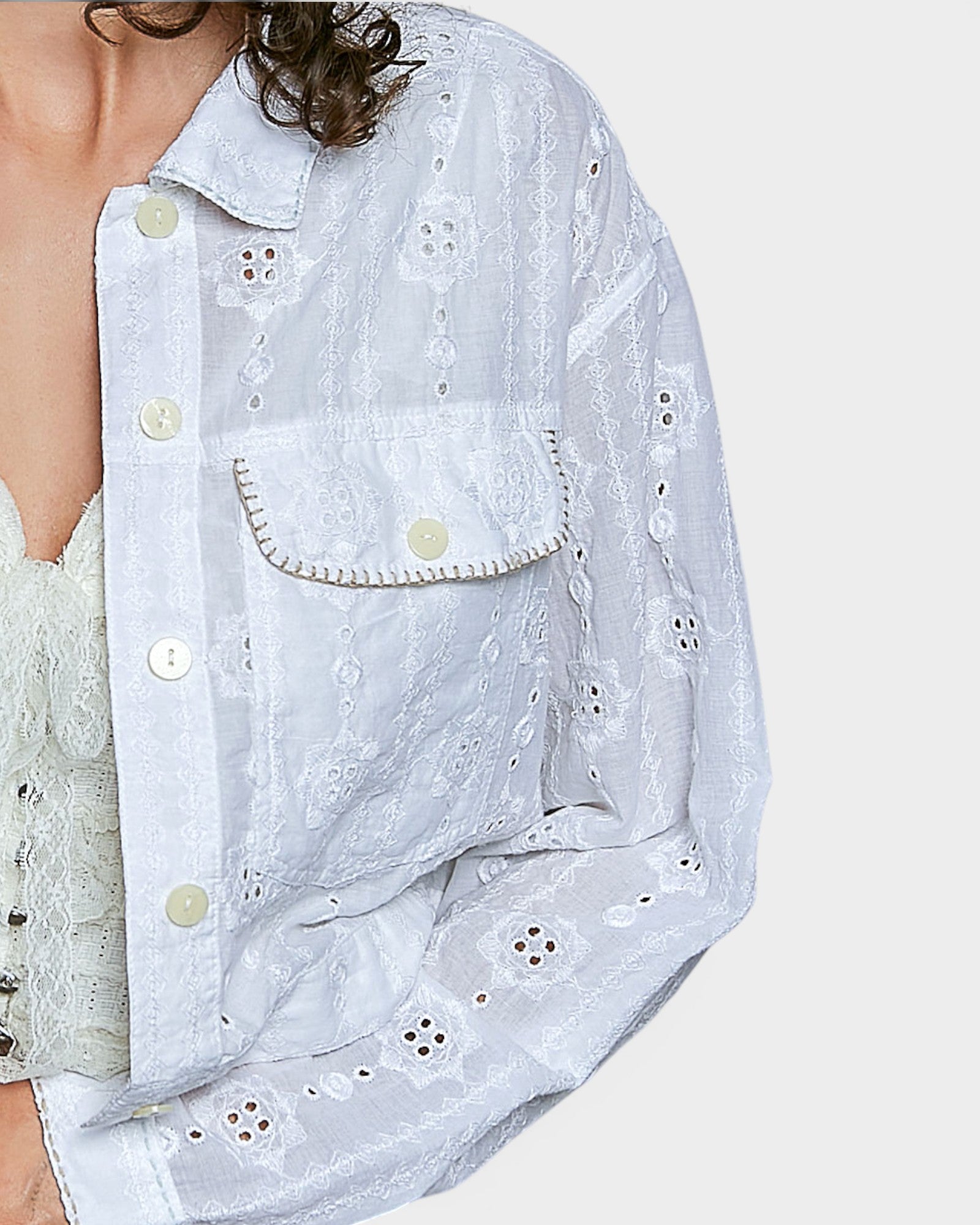 Person wearing an off white embroidered jacket and denim pants on a white background