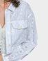 Person wearing an off white embroidered jacket and denim pants on a white background