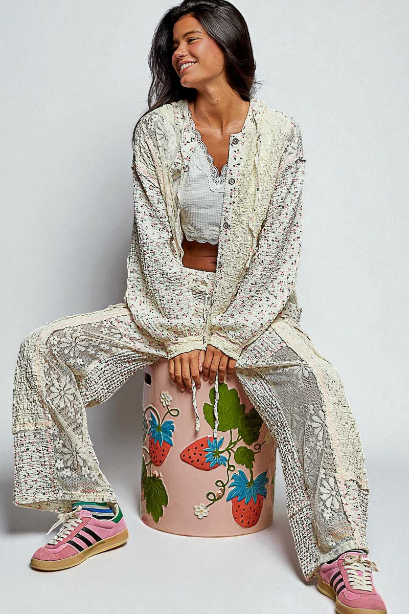 Woman sitting on a decorated stool wearing a matching outfit with a white background