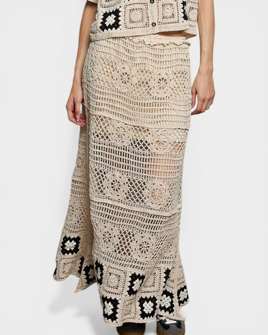 Person wearing a crochet skirt with black floral patterns on a white background