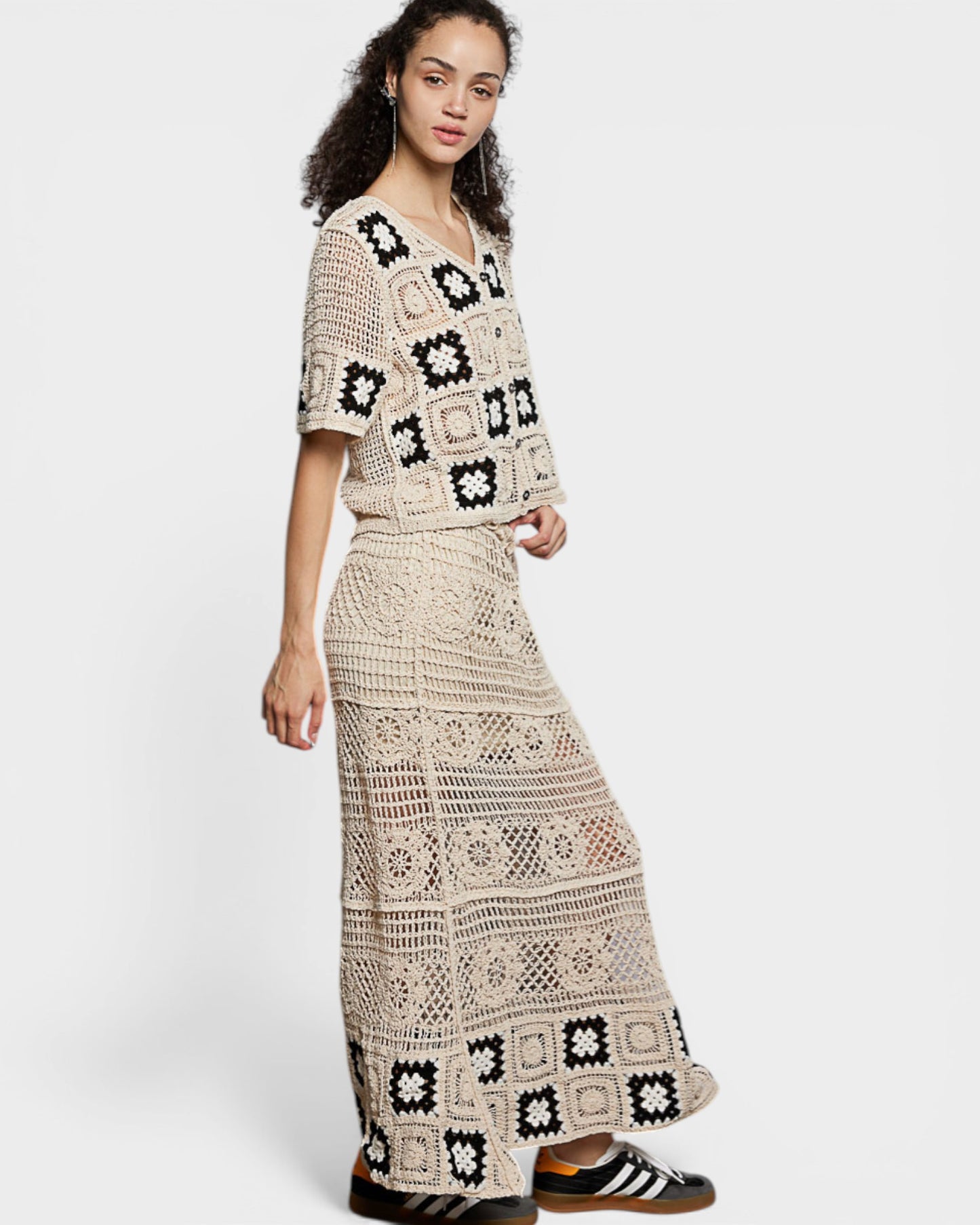 Woman wearing a patterned crochet outfit on a white background