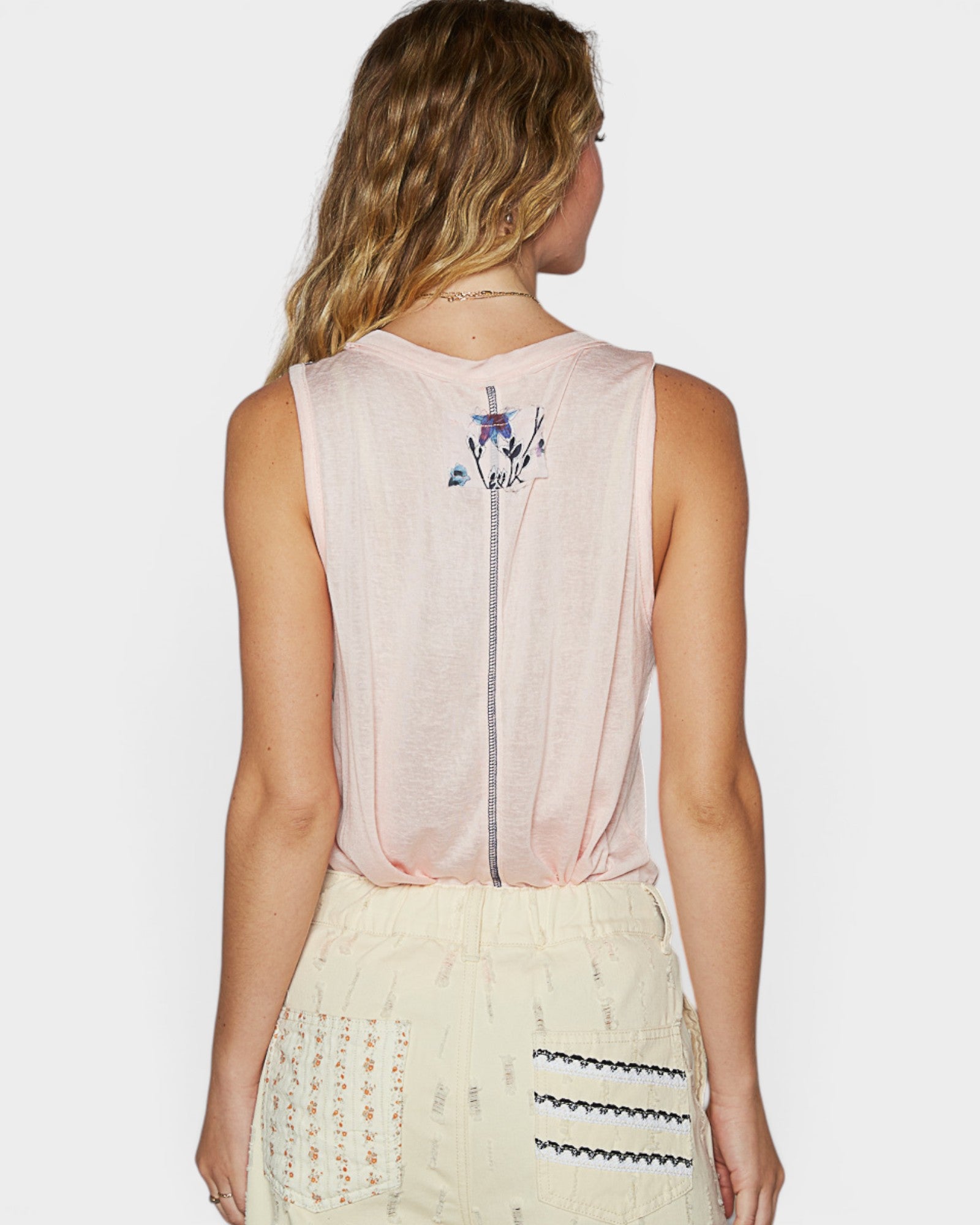 Woman wearing a sleeveless top with a decorative back design on a white background