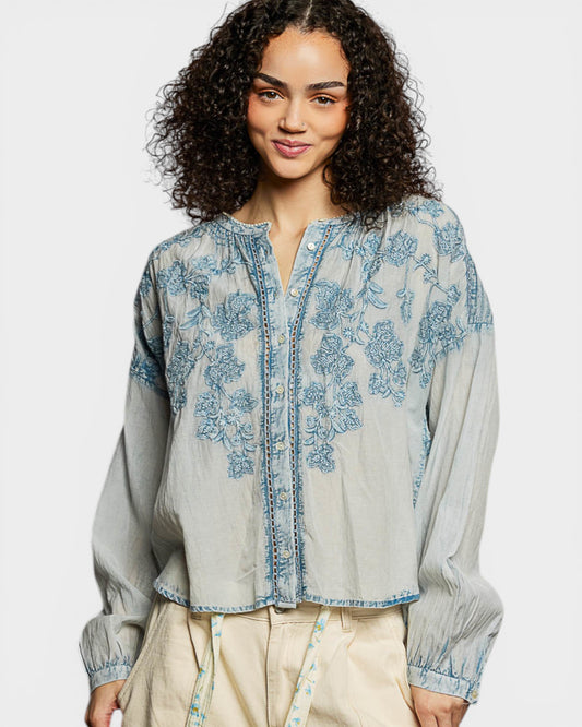 Woman wearing a light blue embroidered blouse on a white background