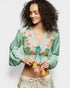Woman wearing a green embroidered blouse with colorful tassels on a white background