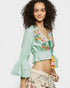 Woman wearing a light green embroidered top with colorful details on a white background
