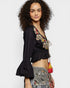 Woman wearing a black embroidered top with colorful details on a white background