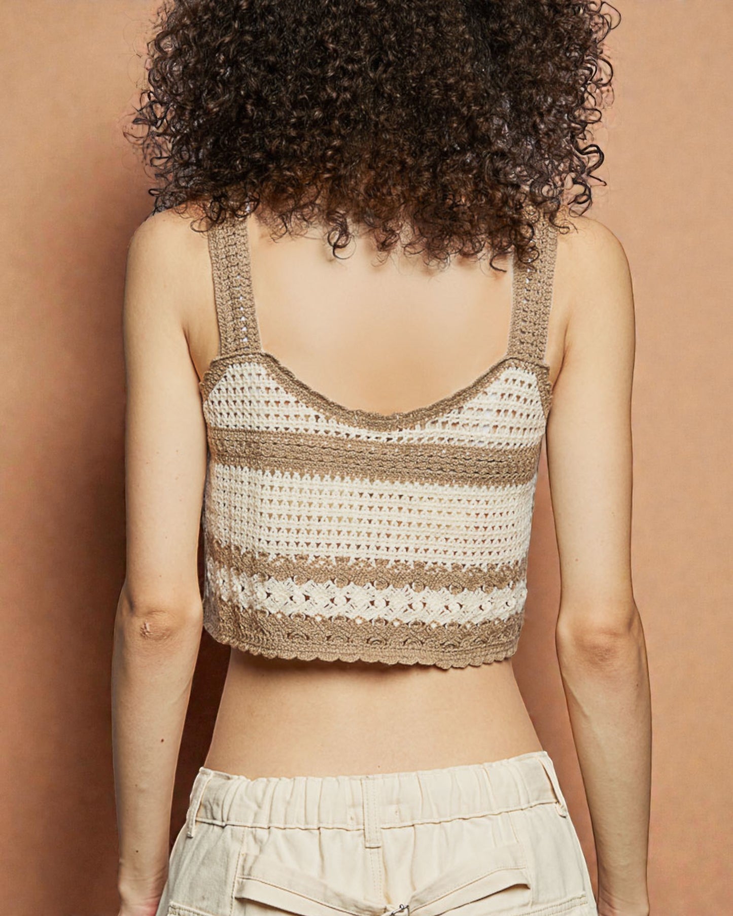 Person wearing a crochet tank top against a brown background