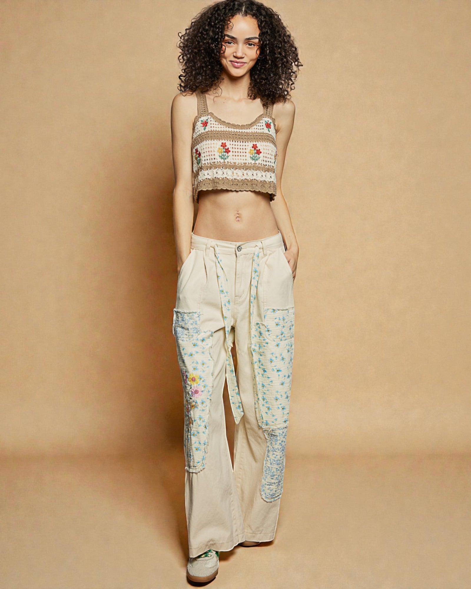 Woman wearing a patterned top and floral pants on a beige background