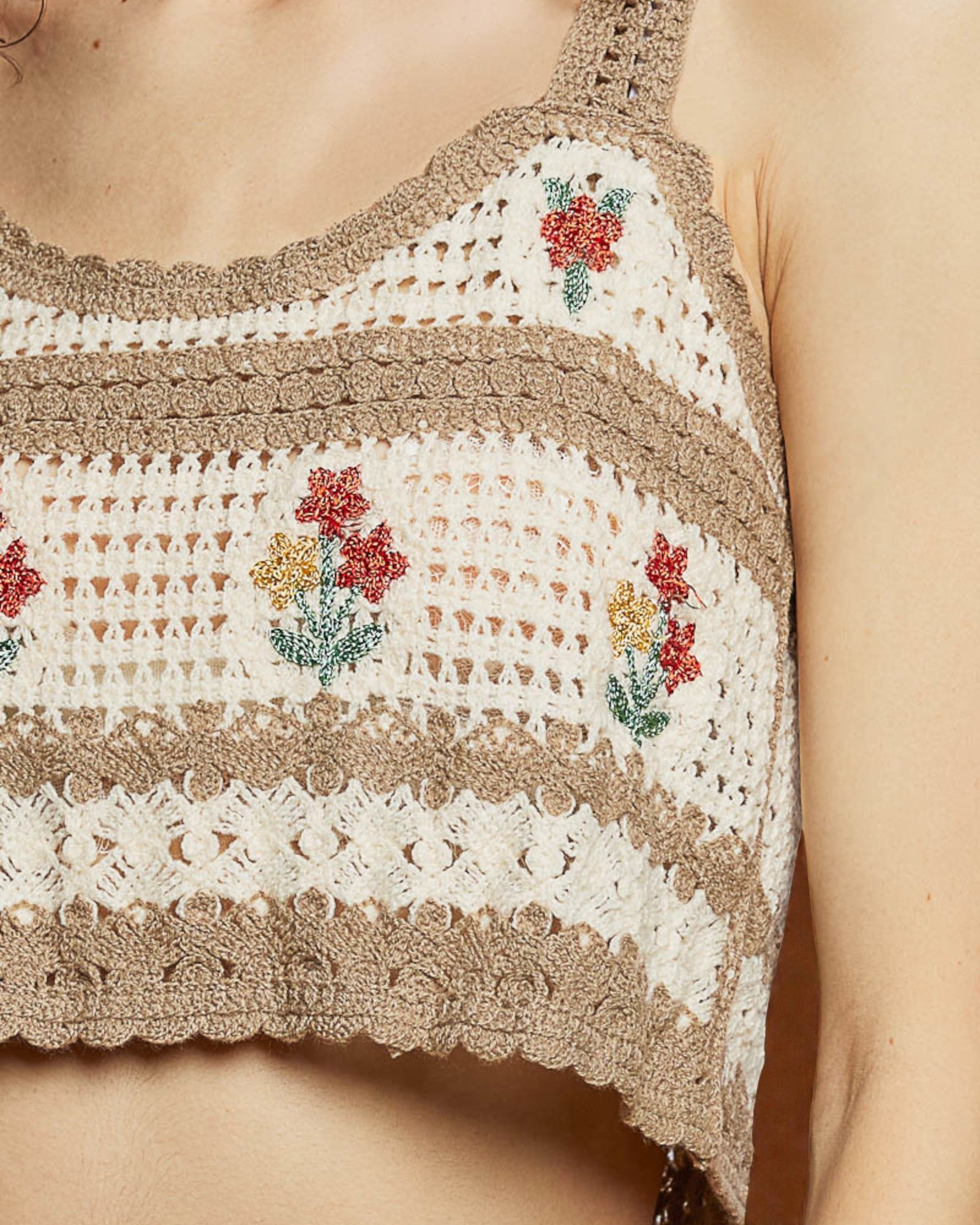 Close-up of a crochet top with floral patterns on a neutral background