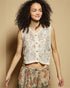 Woman wearing a floral sleeveless top and pants against a beige background
