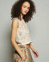 Woman wearing a sleeveless embroidered top and floral skirt against a plain background