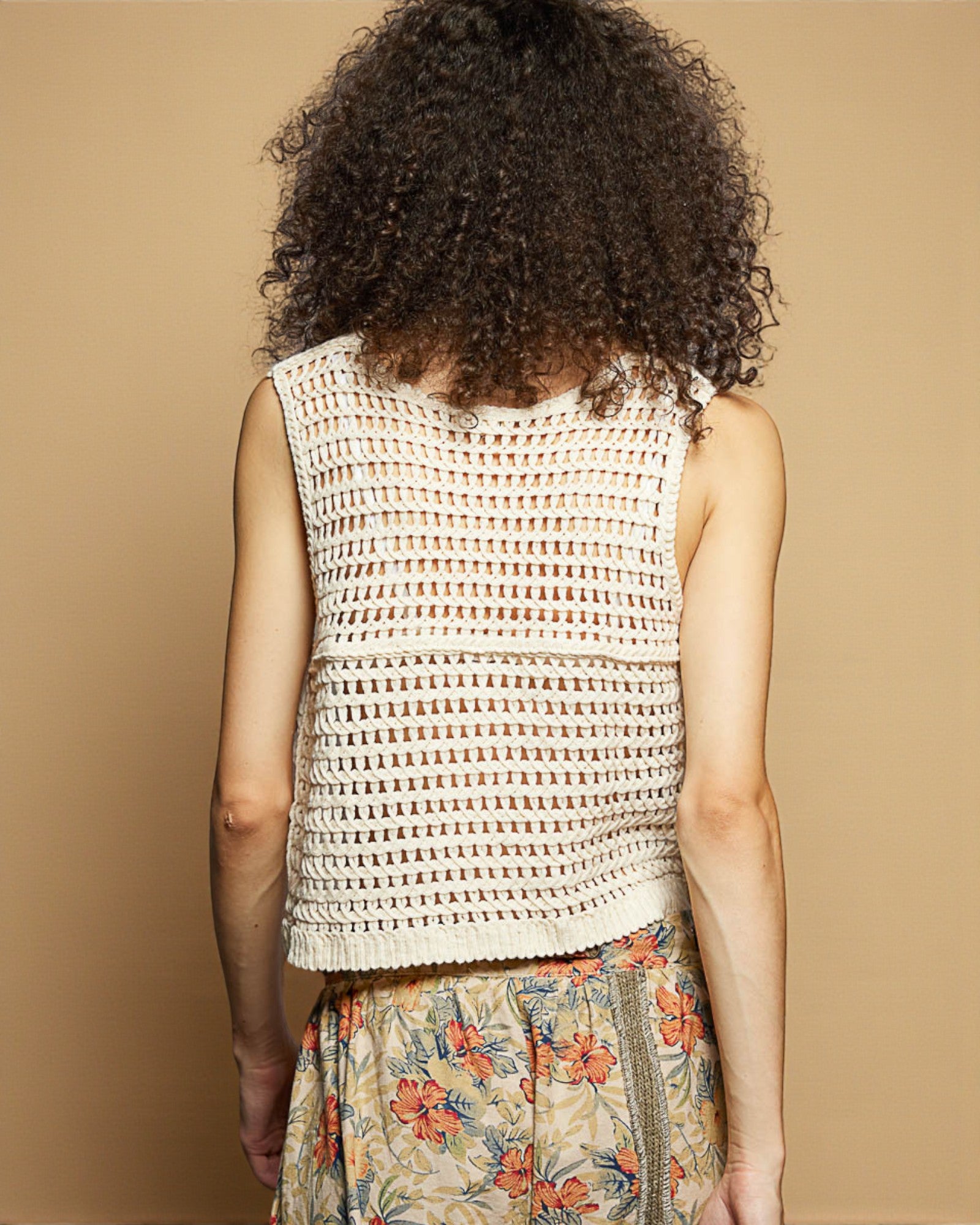 Woman wearing a sleeveless patterned top with a beige background