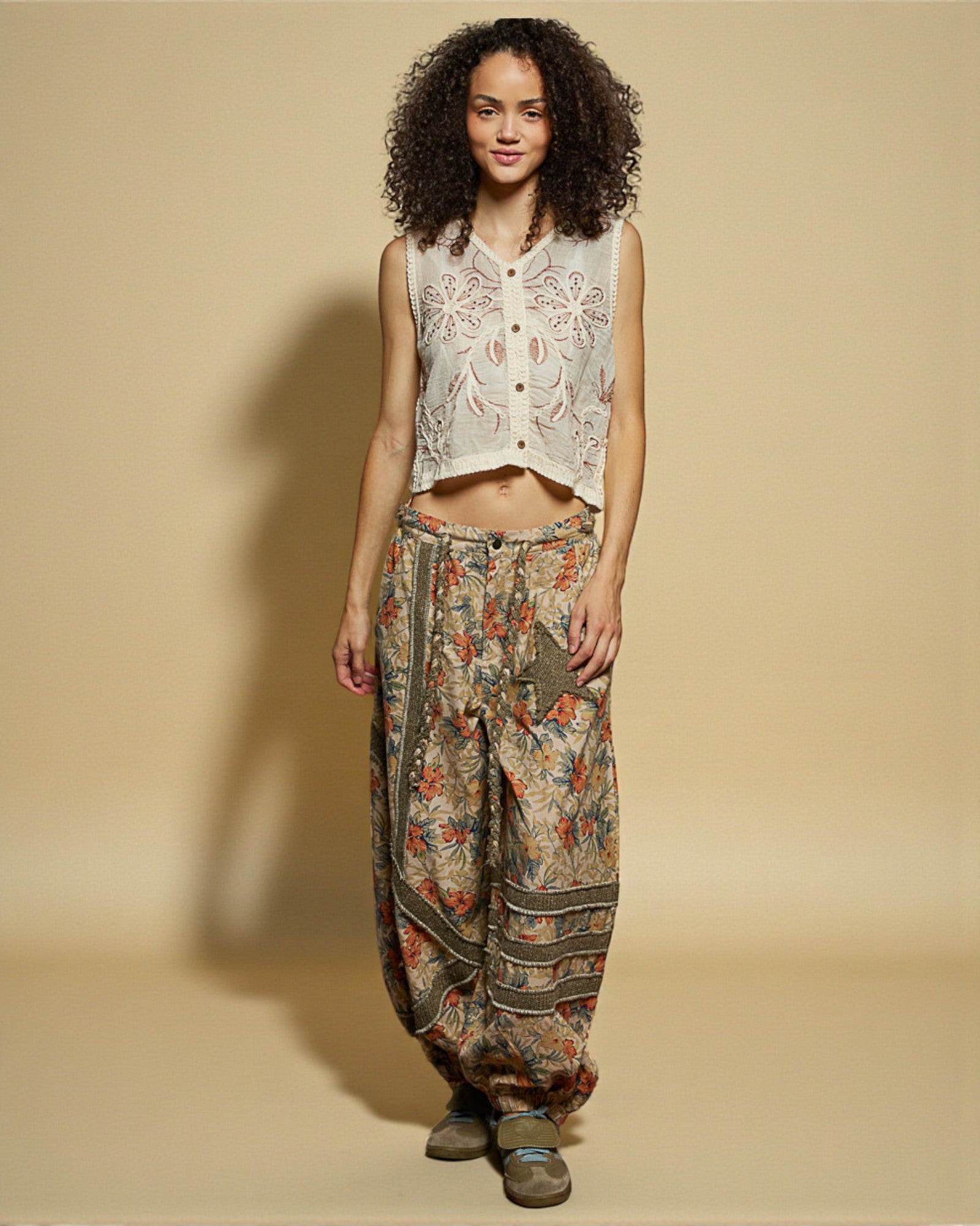 Woman wearing a sleeveless top and patterned pants on a beige background
