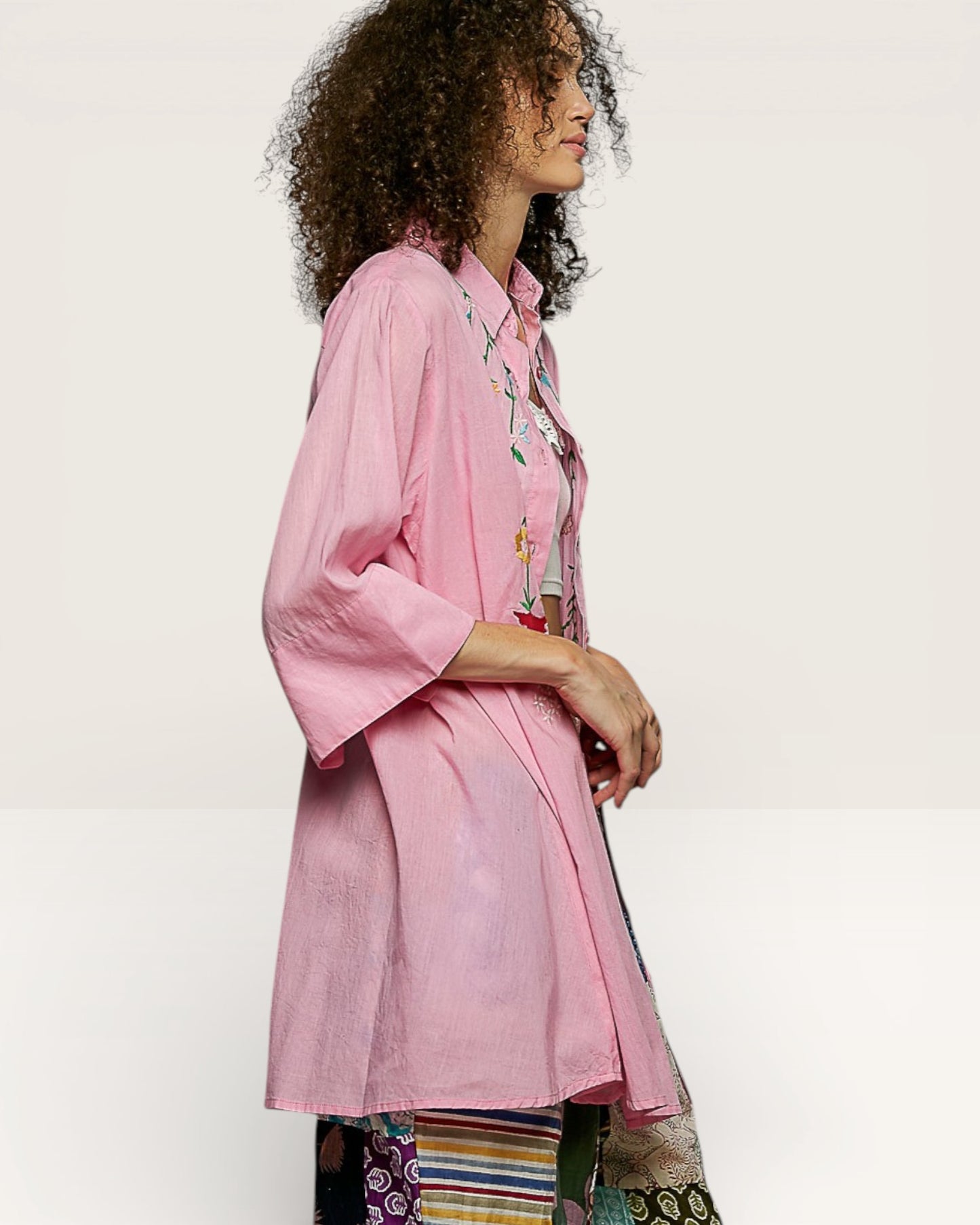Woman wearing a pink embroidered shirt with a white background
