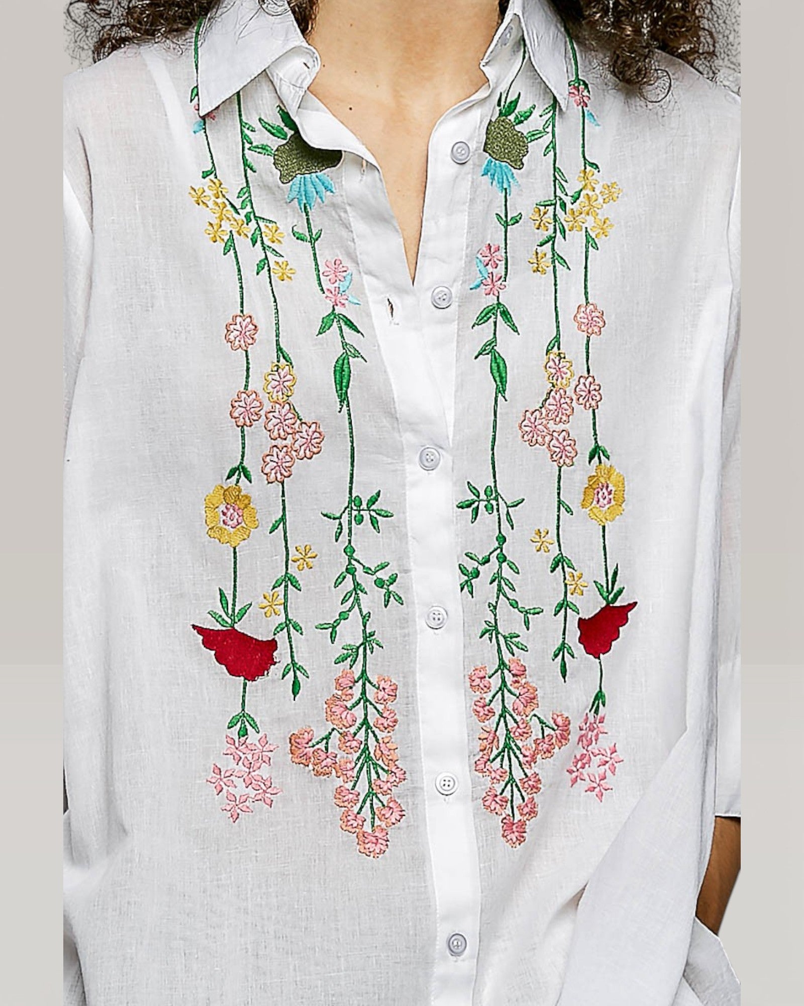 White shirt with colorful floral embroidery on a plain background