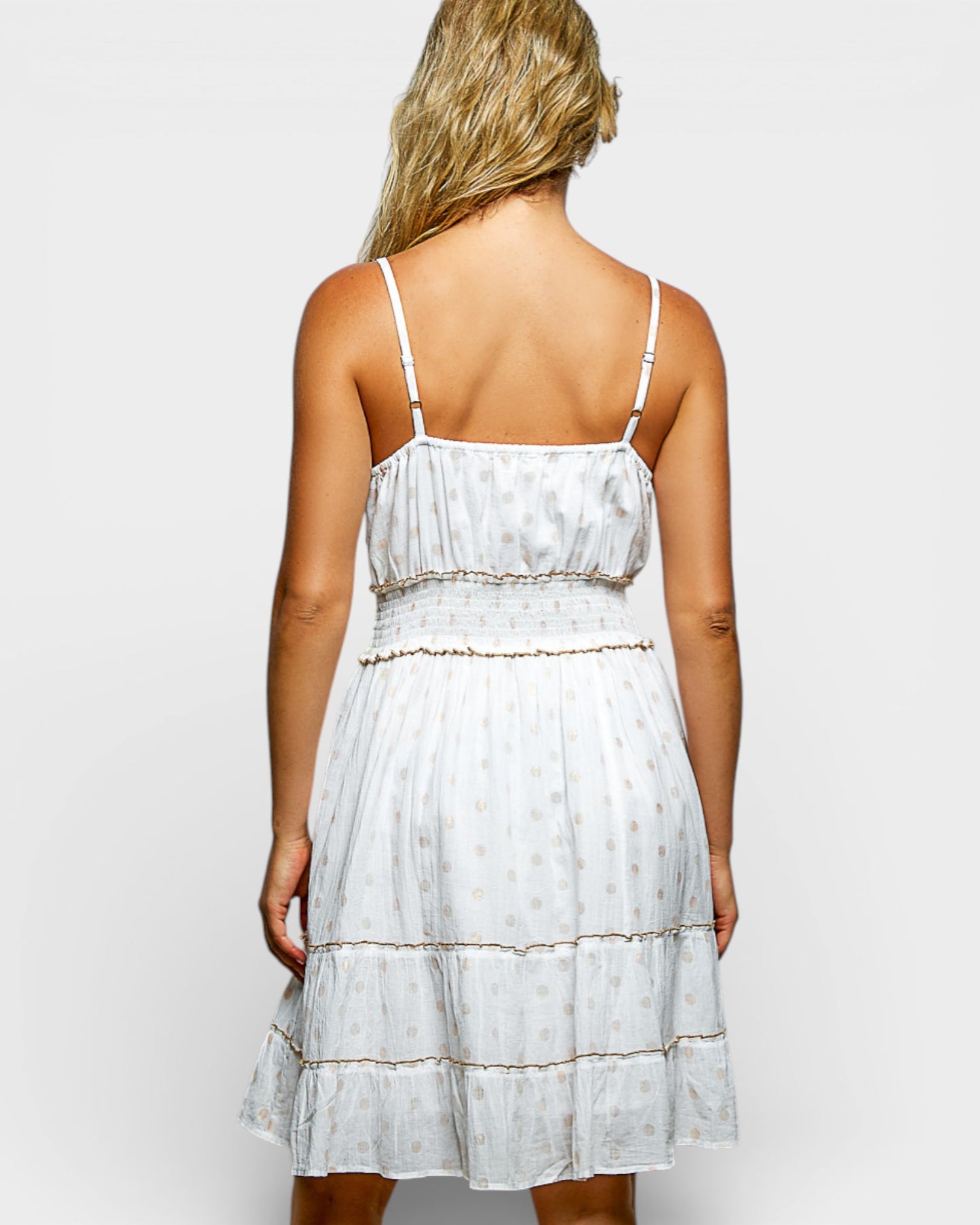 Woman wearing a white dress with thin straps on a plain background