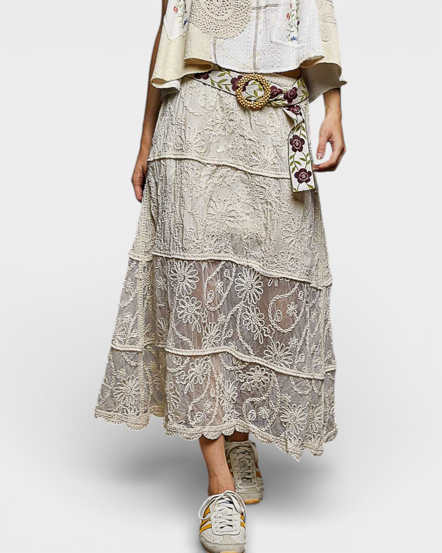 Person wearing a layered lace outfit with a belt and sneakers on a white background