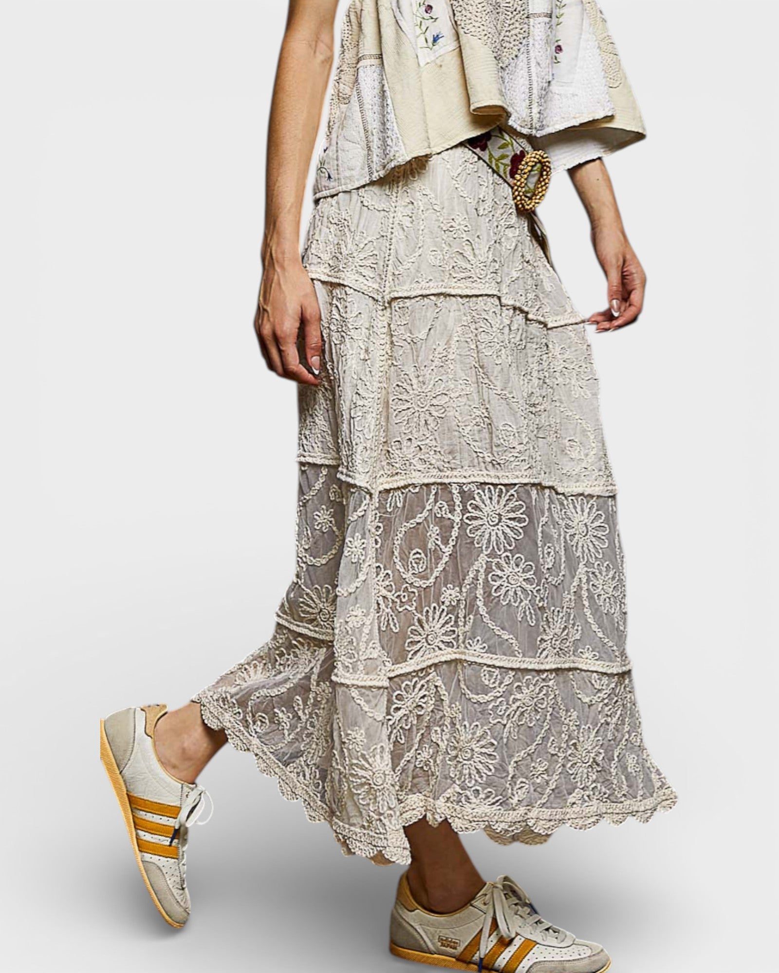 Person wearing a layered lace dress with Adidas sneakers on a white background