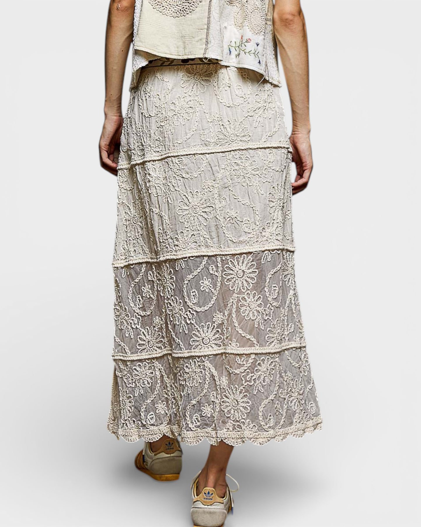 Person wearing a layered lace dress on a white background