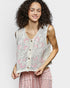 Woman wearing a floral lace vest over a pink dress on a plain background