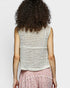 Person wearing a sleeveless crochet top with a plain background