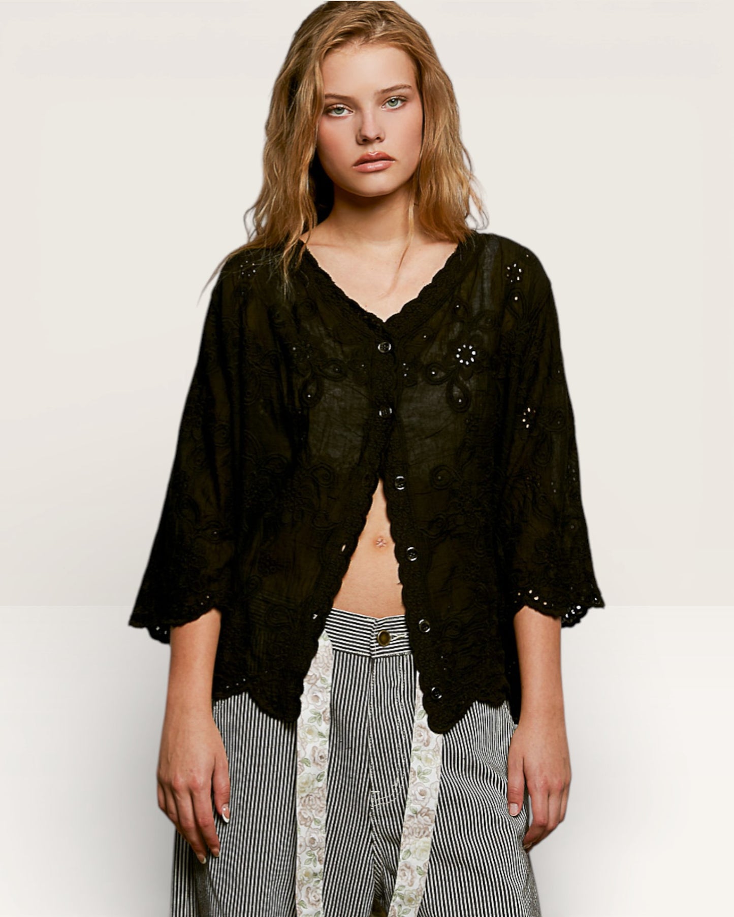 Woman wearing a black lace top and striped pants on a white background