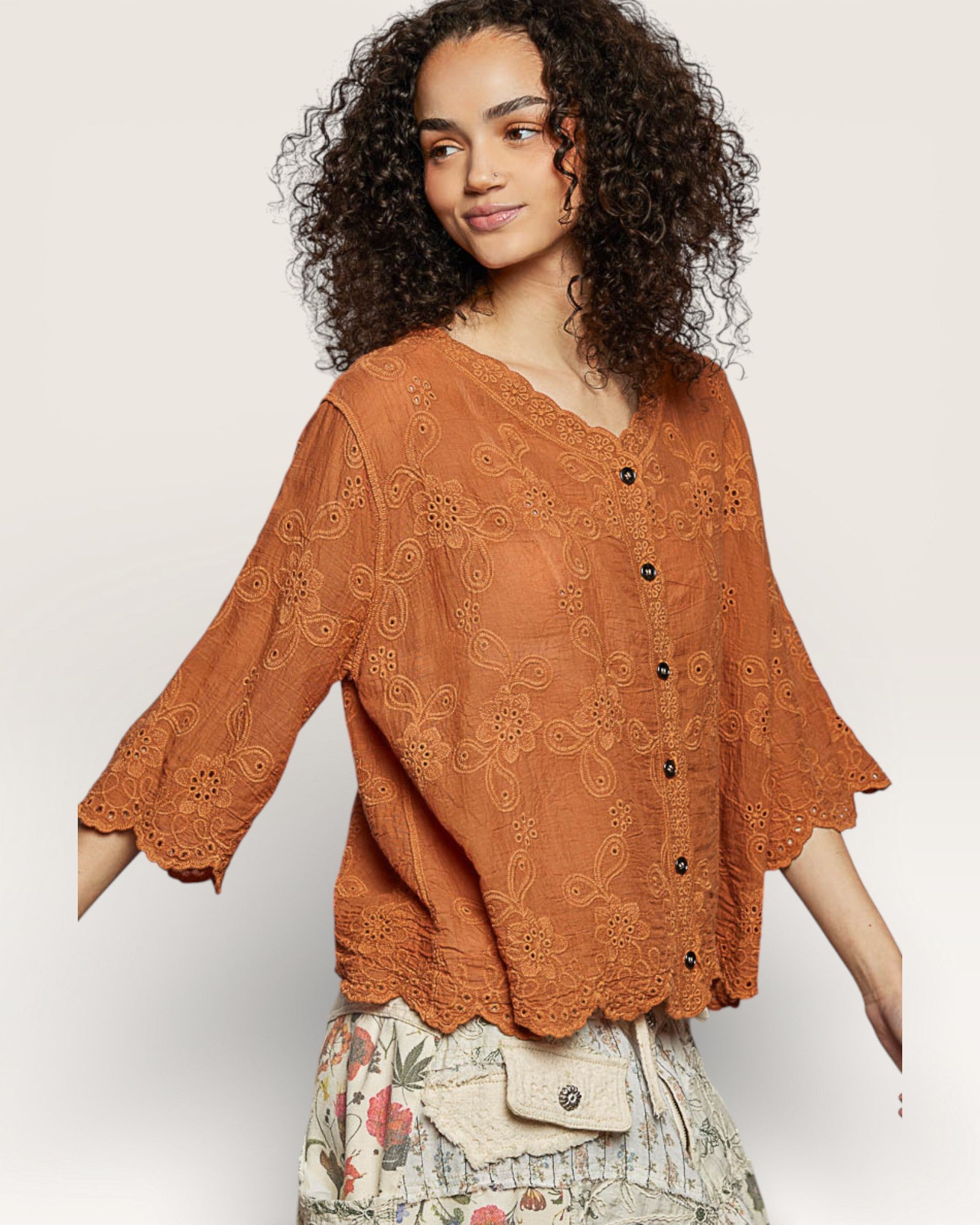 Woman wearing a rust-colored lace top on a white background