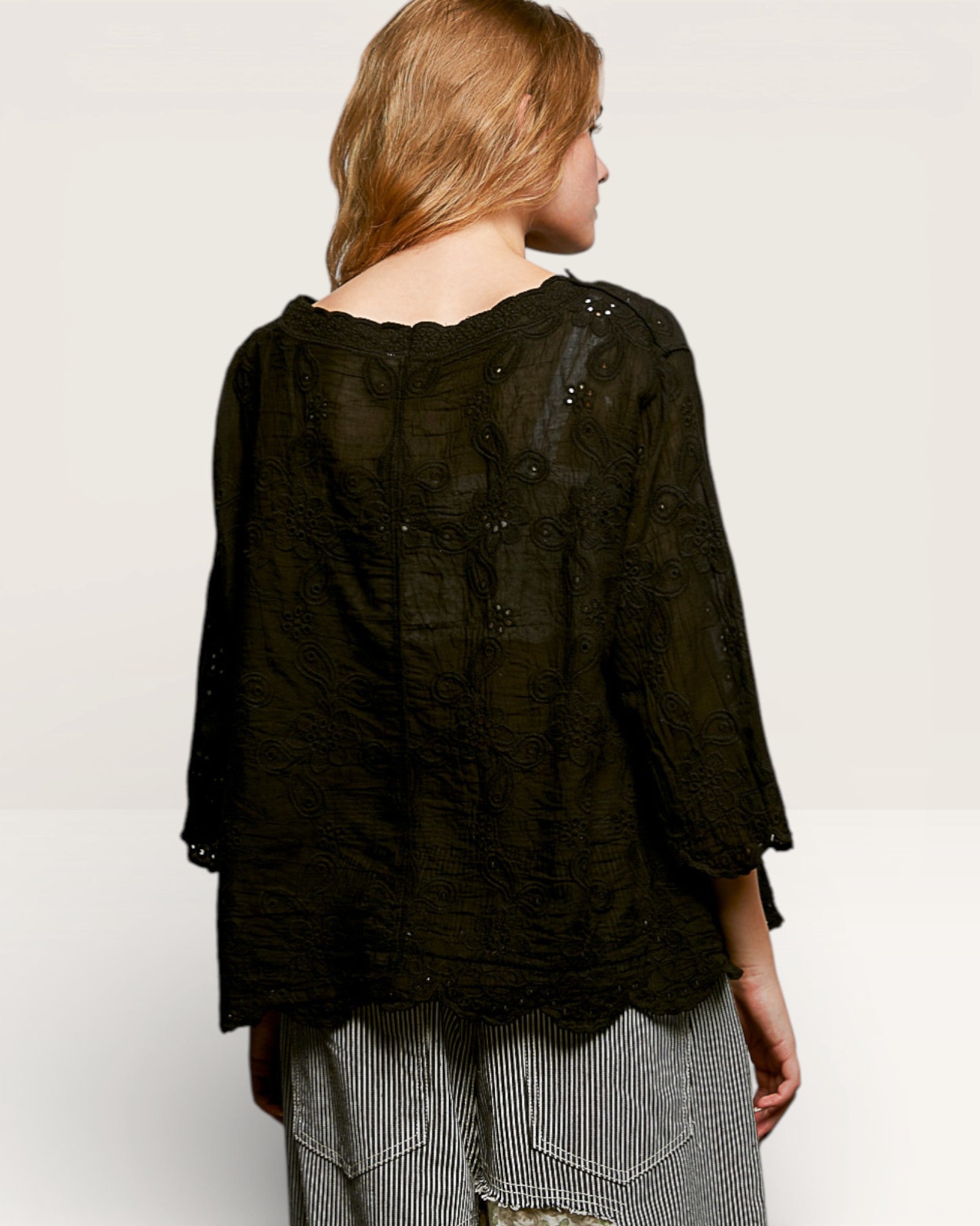 Person wearing a black textured top with a plain background