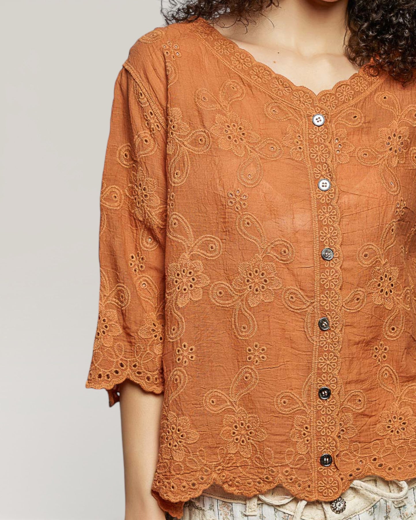 Brown lace top with buttons on a plain background