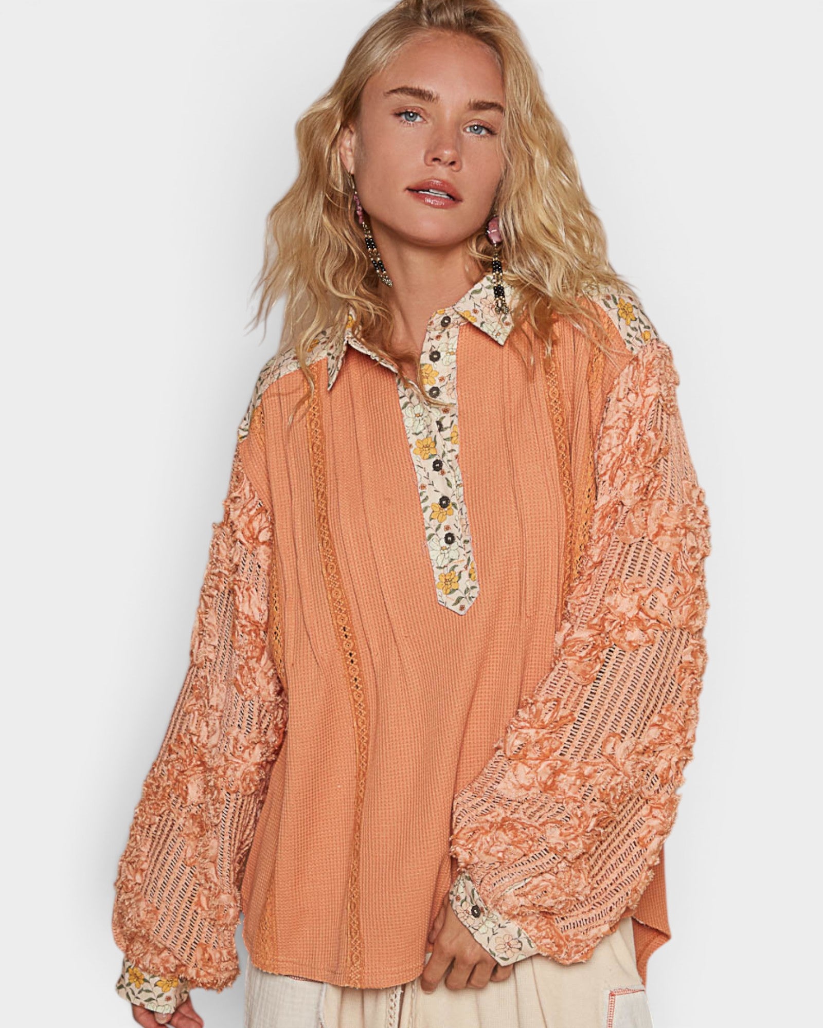 Woman wearing a peach-colored blouse with floral patterns on a white background