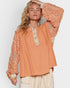 Woman wearing a peach-colored blouse with intricate lace details on a plain background