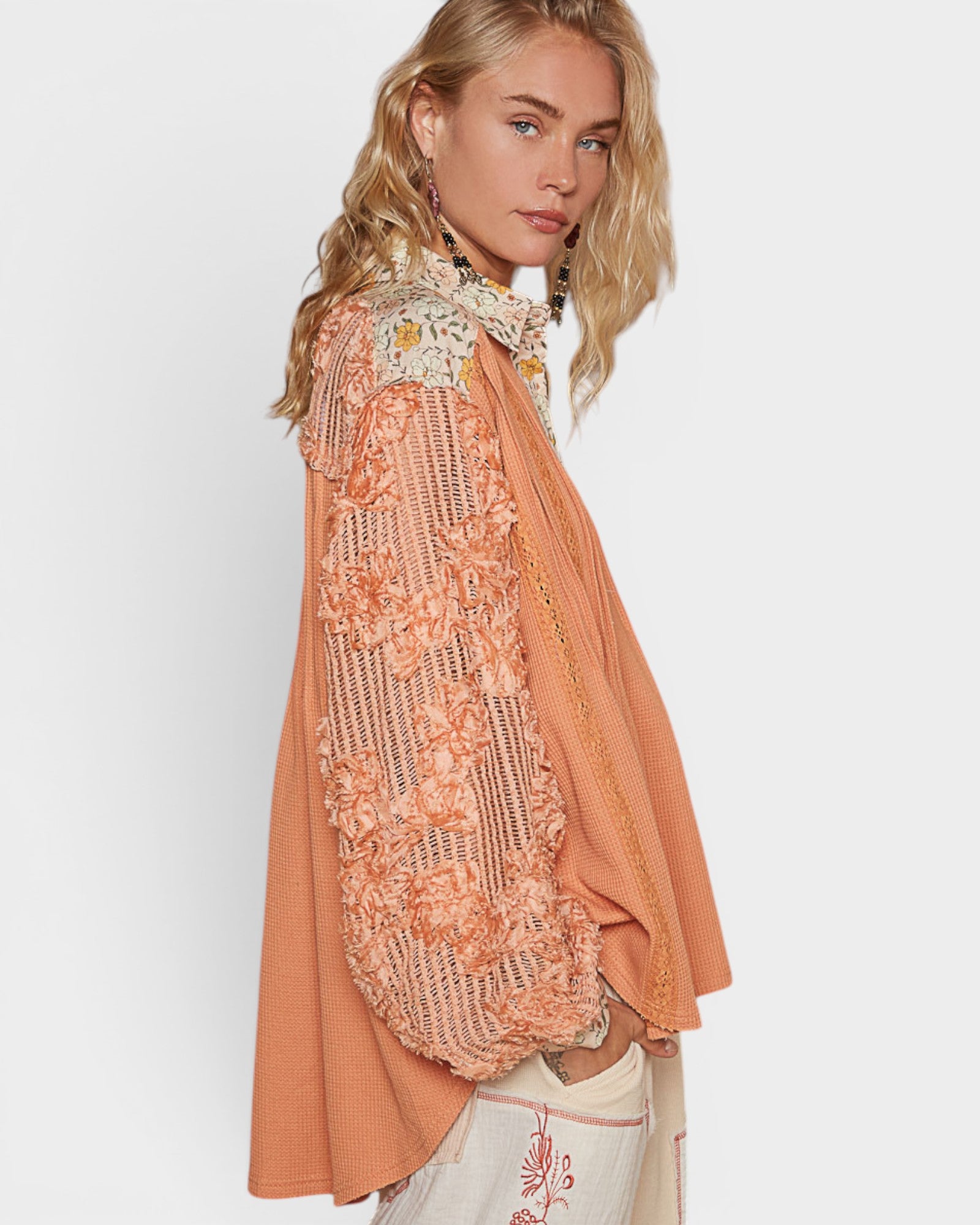 Woman wearing a peach-colored embroidered top with a white background
