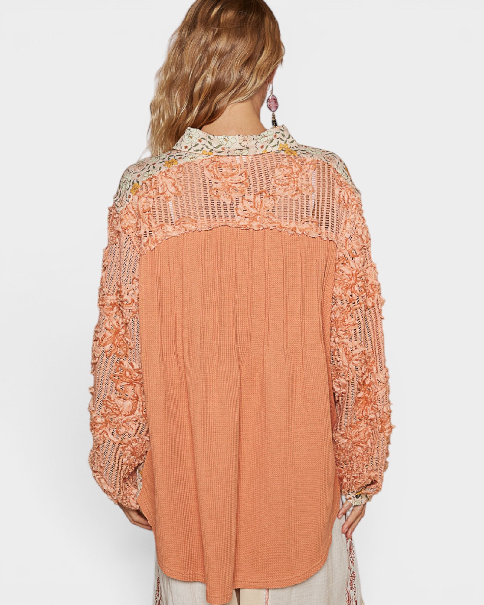 Coral blouse with lace details on a plain background