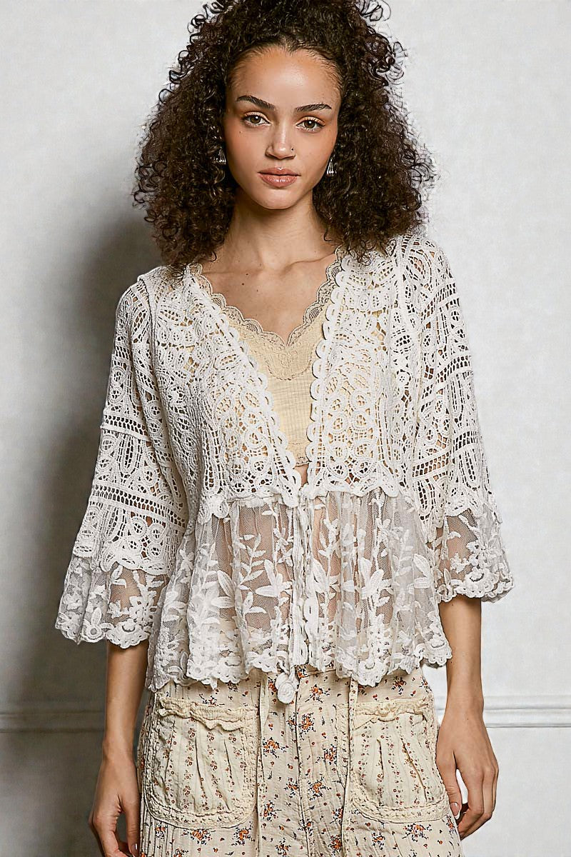 Woman wearing a lace top and floral dress against a plain background