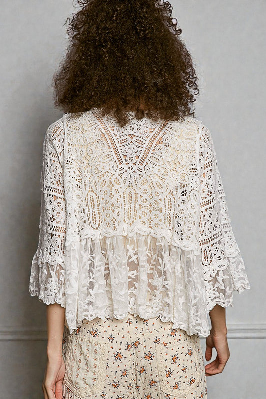 Person wearing a white lace top against a gray background
