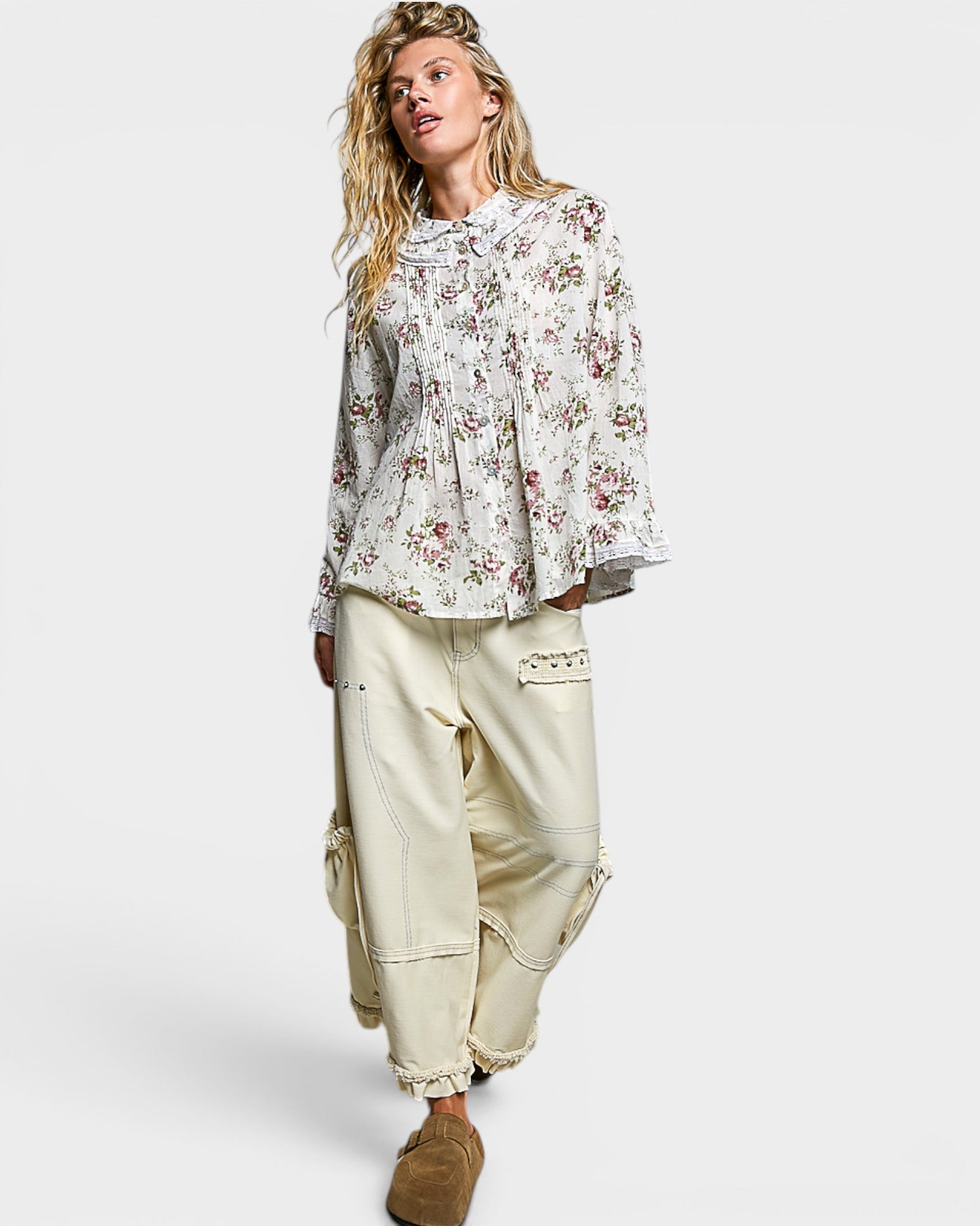 Woman wearing a floral blouse and beige pants on a white background