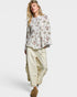 Woman wearing a floral blouse and beige pants on a white background