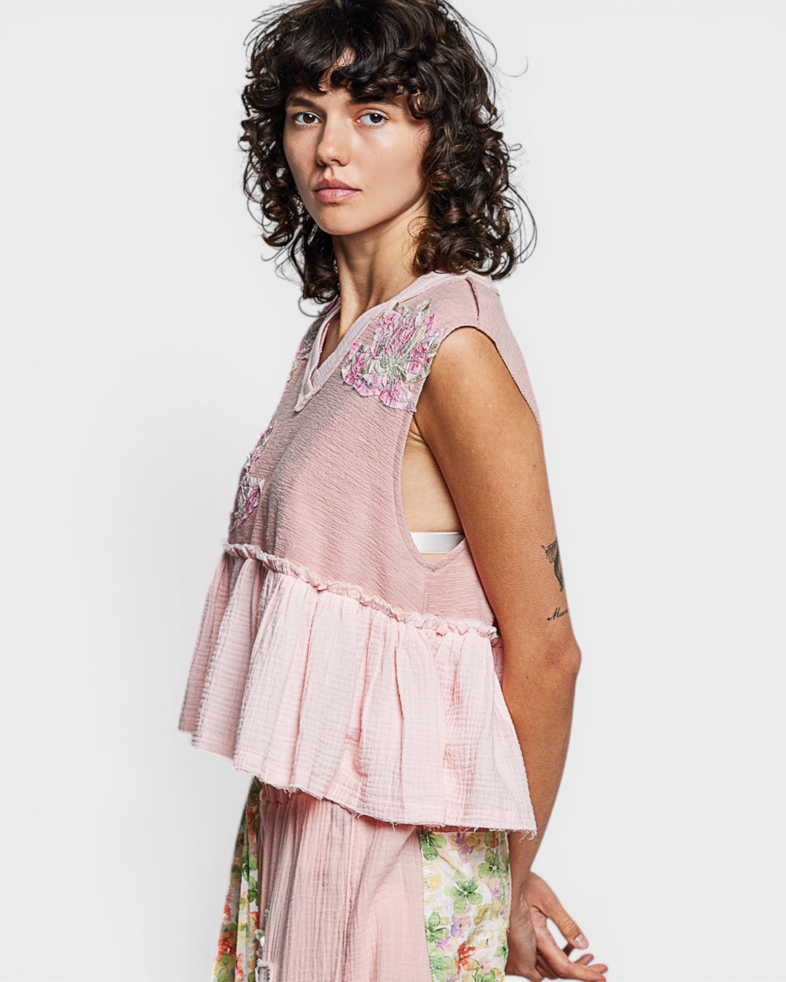 Woman wearing a pink embroidered top with a white background
