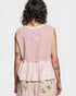 Person wearing a pink sleeveless top with floral patterns on a plain background