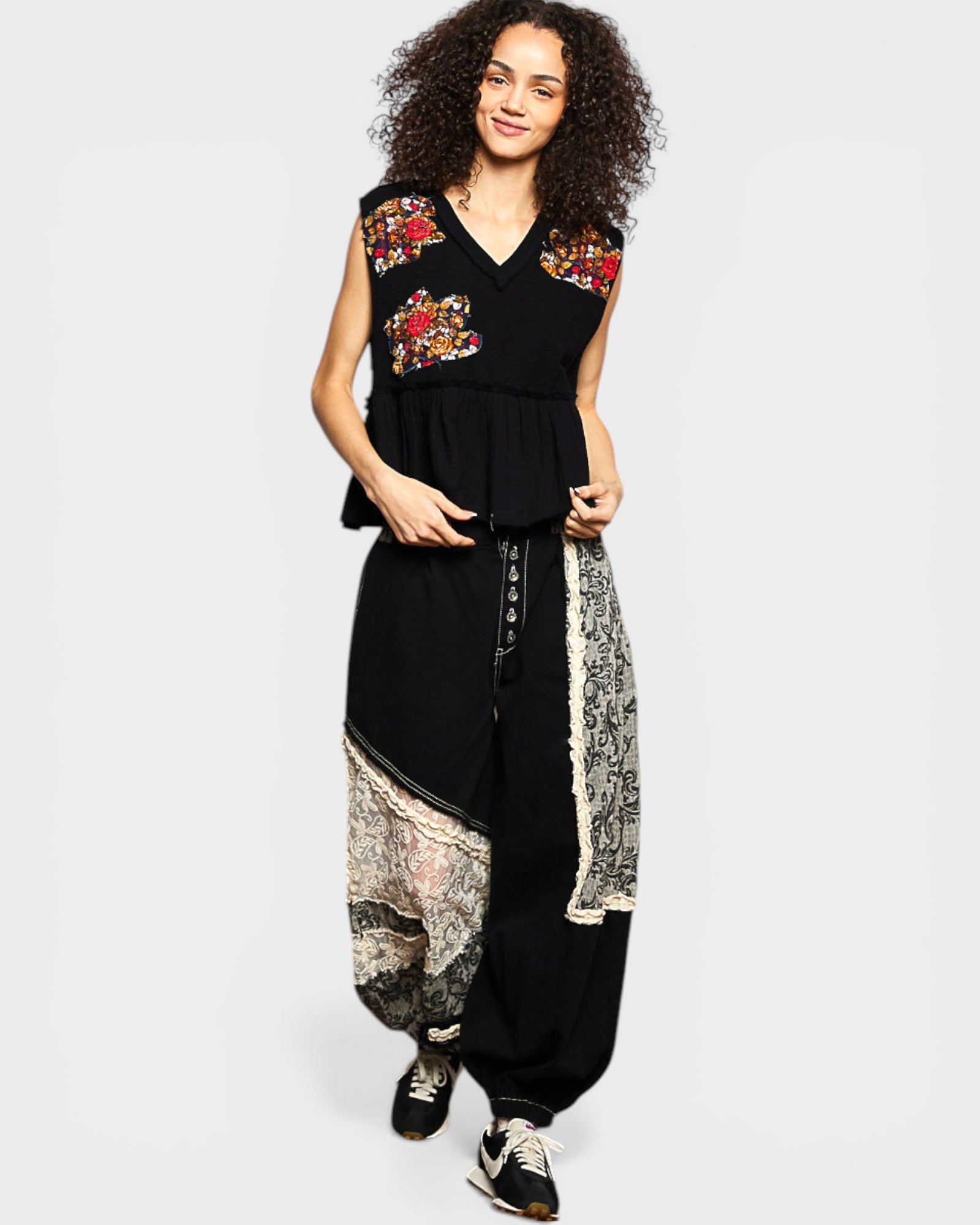 Woman wearing a black outfit with floral embroidery on a white background